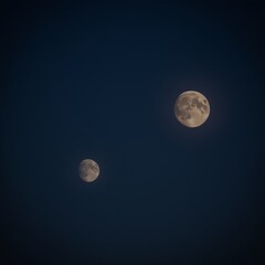 Two full moons are in the sky, one is on the left and the other is on the right