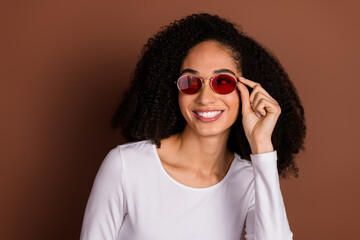 Canvas Print - Portrait of nice young woman touch sunglass look empty space wear pullover isolated on brown color background