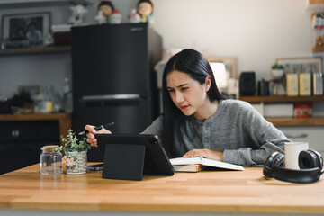 Poster - Young woman engaged in studying at home using a tablet and taking notes in a notebook, surrounded by a cozy and modern kitchen environment.