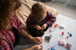 © Andrii Lysenko - Mother and baby are making a model from plasticine or from toy colored dough, view from above