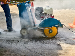 A worker using a grinder machine to cut a concrete floor.