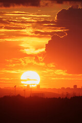Wall Mural - Sunset over cityscape with silhouette of cranes and buildings against an orange sky. City skyline photography for poster, wallpaper, banner, vertical.