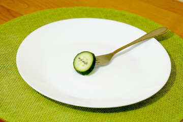 a circle of sliced cucumber skewered on a fork on a white plate