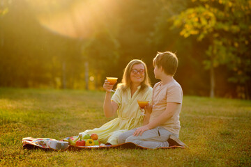 A cheerful woman and her teenage son were enjoying a picnic together in the summer sunshine. The family spent a delightful afternoon outdoors, with the mother and her child boy smiling