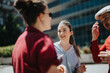 © qunica.com - Group of young business professionals discussing plans outdoors during a sunny day. They appear cheerful and engaged in conversation.