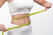 © Валерия Стоганенко - Cropped view of the sporty woman measuring waist with yellow tape against white background. Weight loss and diet concept.