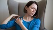 © SMPTY - Woman Suffering from Shoulder Pain at Home, Experiencing Discomfort and Muscle Strain While Sitting in Chair