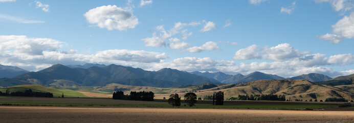 A beautiful panorama view of colorful farmland and mountain range along the adventure roadtrip, South Island, New Zealand.