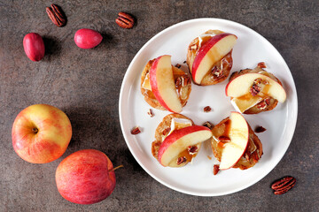 Poster - Plate of crostini appetizers with red apples, brie cheese and walnuts. Top view table scene against a dark background. Party food concept.