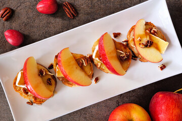 Poster - Crostini appetizers with red apples, brie cheese and walnuts. Above view table scene against a dark background. Party food concept.