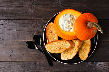 Aufkleber - Autumn pumpkin theme appetizer with spinach dip and toasted baguettes. Overhead view against a dark wood background. Fall party food concept.
