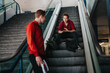 © qunica.com - Two business colleagues engaging in a serious conversation on an escalator in an urban building. Professional attire and expressions reflect a deep, important discussion.
