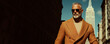 © Augustino - High fashion concept. Portrait of fashionable mature male model walking in luxurious clothing among Ney York skyscrapers. Luxury brands campaign style. Banner. Outdoor shot