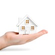 © ruangrit19 - Macro Hand Holding Miniature House Cutout on White Background