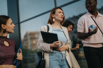 Wall Mural - A diverse group of business people engaging in a discussion outside an office building, showcasing teamwork and collaboration in a business environment.