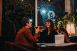 © qunica.com - A couple enjoys cocktails in a warmly lit restaurant, creating a romantic and intimate atmosphere. The night scene highlights their joyful interaction and relaxed mood.