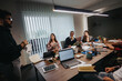 © qunica.com - A focused team of business professionals are engaged in a meeting within a well-equipped office, analyzing growth charts while discussing strategic plans.