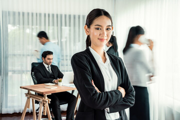 Portrait of happy young asian businesswoman looking at camera with motion blur background of business people movement in dynamic business meeting. Habiliment