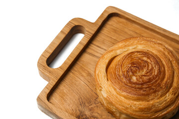 Close up view of freshly baked cinnamon roll served on wooden cutting board isolated on white background