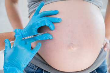 Wall Mural - Doctor gives an injection in the stomach of a pregnant woman. 