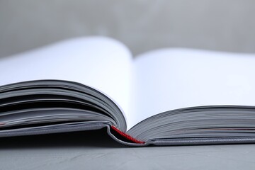 Wall Mural - Open book with hard cover on grey table, closeup