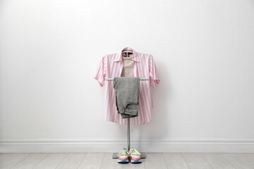 Canvas Print - Rack with clothes and shoes near white wall in hallway