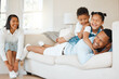 © KayExam/peopleimages.com - People, kids and together for games in living room with growth, support and care in cheerful, play and fun. Man, woman and children as parents for happiness, love and bonding in family home or lounge