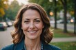 © ThomasLENNE - Close portrait of a smiling 40s American woman looking at the camera, American outdoors blurred background