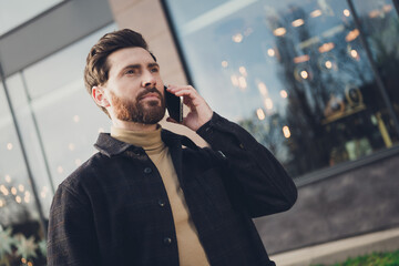 Poster - Photo of young successful man walking city street autumn day talking modern device outside