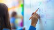 © Morning - A young student writes on a whiteboard in a classroom.