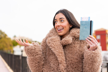 Wall Mural - Young woman holding a passport at outdoors with surprise facial expression