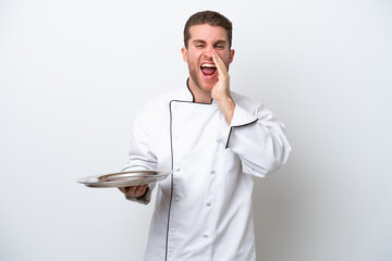 Wall Mural - Young caucasian chef with tray isolated on white background shouting with mouth wide open