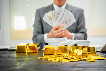 Businessman in suit sits at his desk, holding a shining gold bar. financial charts, the scene symbolizes wealth, investment success, growing influence of cryptocurrency and blockchain.