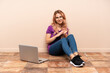 © luismolinero - Teenager woman with a laptop sitting on the floor at indoors applauding after presentation in a conference