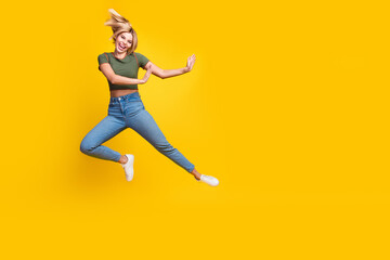 Poster - Full size photo of positive girl dressed khaki crop top jeans jump out of object in empty space isolated on yellow color background