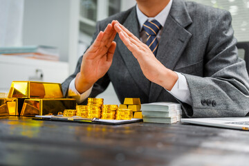 Businessman in suit sits at his desk, holding a shining gold bar. financial charts, the scene symbolizes wealth, investment success, growing influence of cryptocurrency and blockchain.