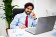 © Minerva Studio - Smiling mid adult businessman talking on phone in office