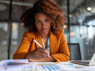 Aufkleber - focused woman in orange blazer analyzes data charts at modern office desk, showcasing determination and professionalism