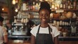 © liliyabatyrova - A smiling woman wearing a black apron stands behind a counter in a coffee shop