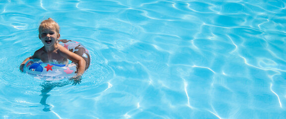 Сheerful child girl is played swimming with an inflatable ring in a summer pool. Banner