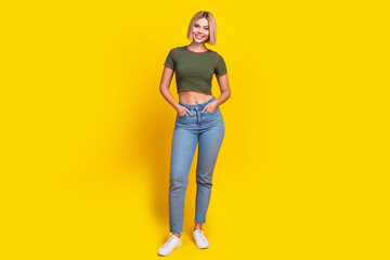 Canvas Print - Full length photo of adorable pretty girl dressed khaki t-shirt jeans holding palms in pockets isolated on yellow color background