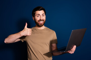 Aufkleber - Photo portrait of brunet hair software engineer man in beige t shirt using laptop working online show like sign isolated on dark blue color background