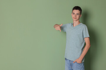 Wall Mural - Teenage boy wearing light grey t-shirt on green background, space for text