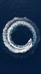 Wall Mural - aerial top view of a fast motor rib boat forming a circles of waves and bubbles with its engine over