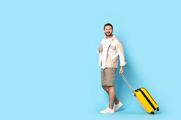 Wall Mural - Happy man with suitcase on light blue background, space for text