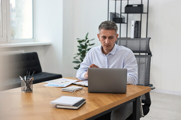 Wall Mural - Banker with laptop working at wooden table in office