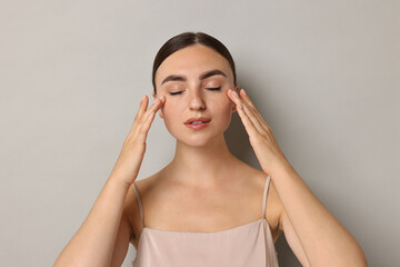 Canvas Print - Face massage. Beautiful young woman with healthy skin on grey background