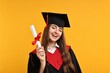 © New Africa - Happy student with diploma after graduation on orange background