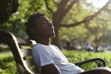 A relaxed individual savors a sunny day on a park bench, eyes closed and soaking in the warm rays, with greenery creating a serene backdrop.