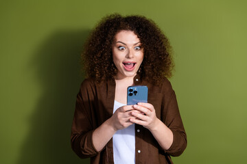 Wall Mural - Photo of pretty young woman open mouth use phone wear brown shirt isolated on khaki color background